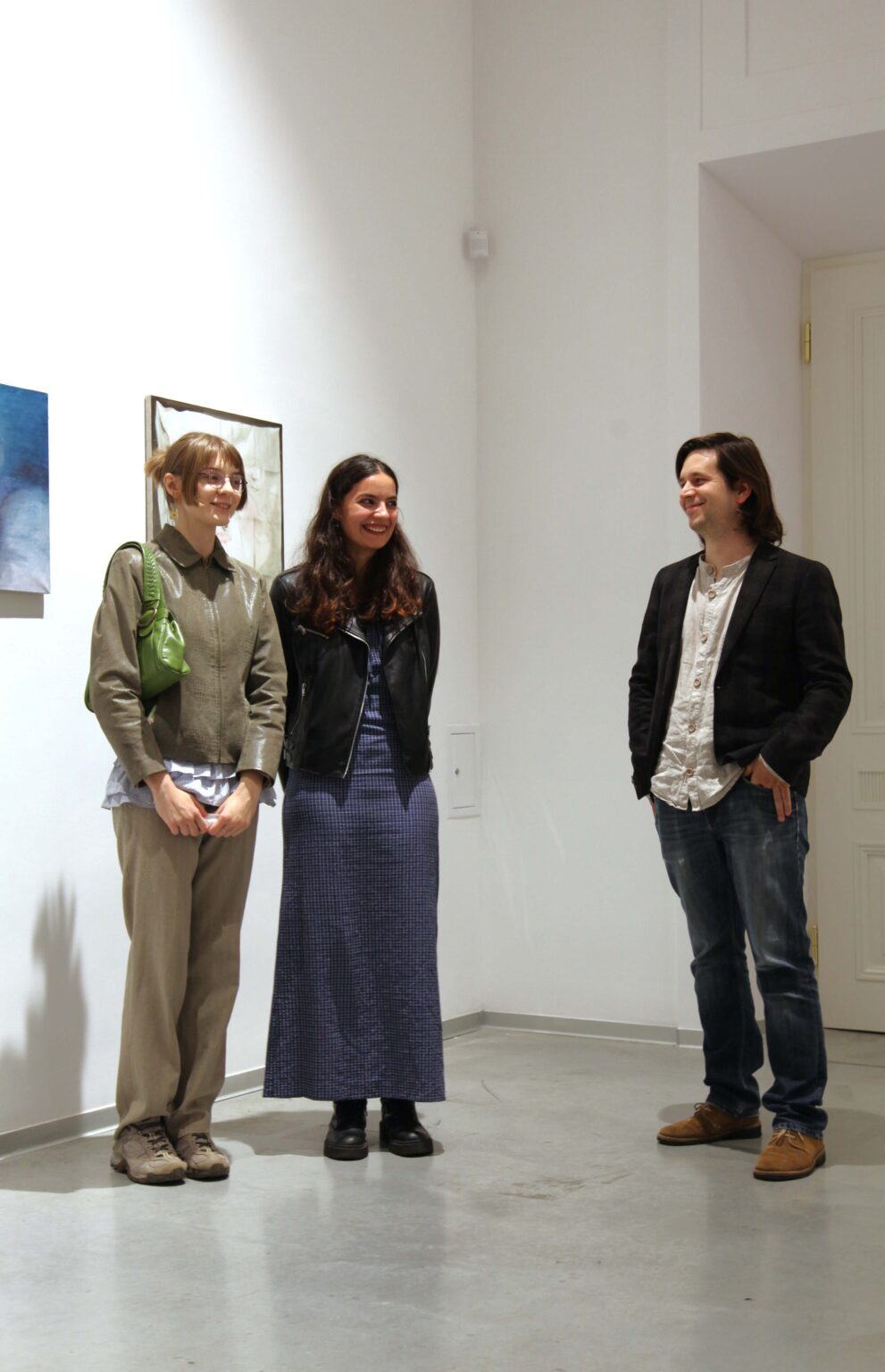 Trzy osoby. Obrazy w tle.