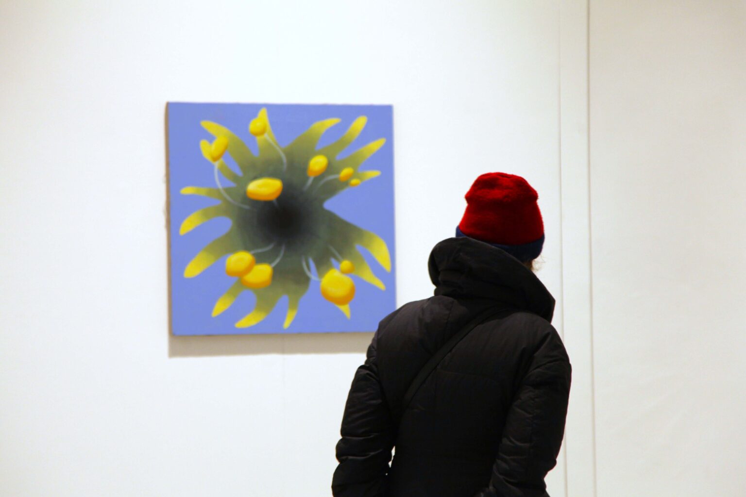 Osoba w czapce ogląda obraz