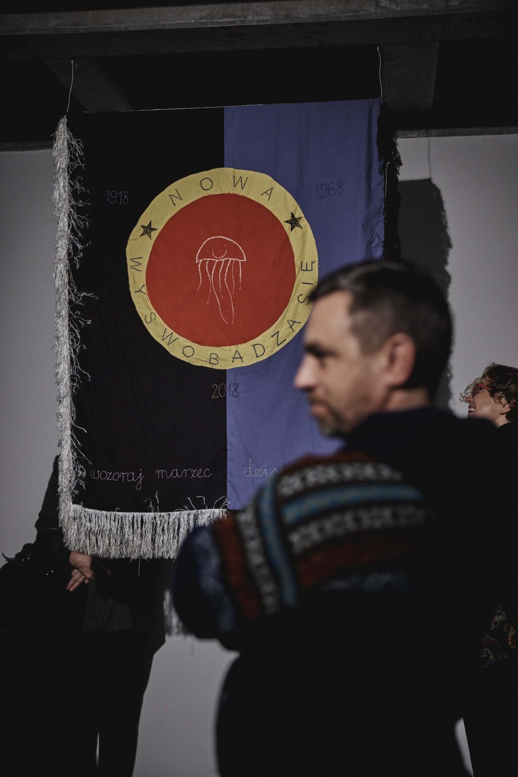 Osoba stoi na tle eksponatu w formie flagi