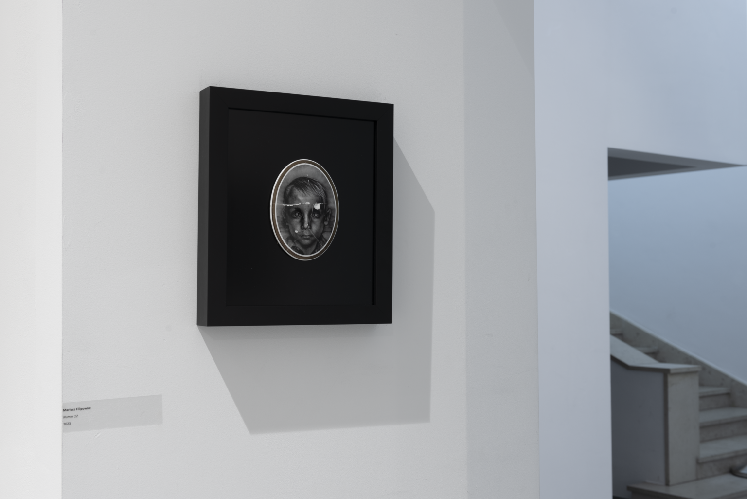 Twarz męska w ciemnej ramce na ścianie.