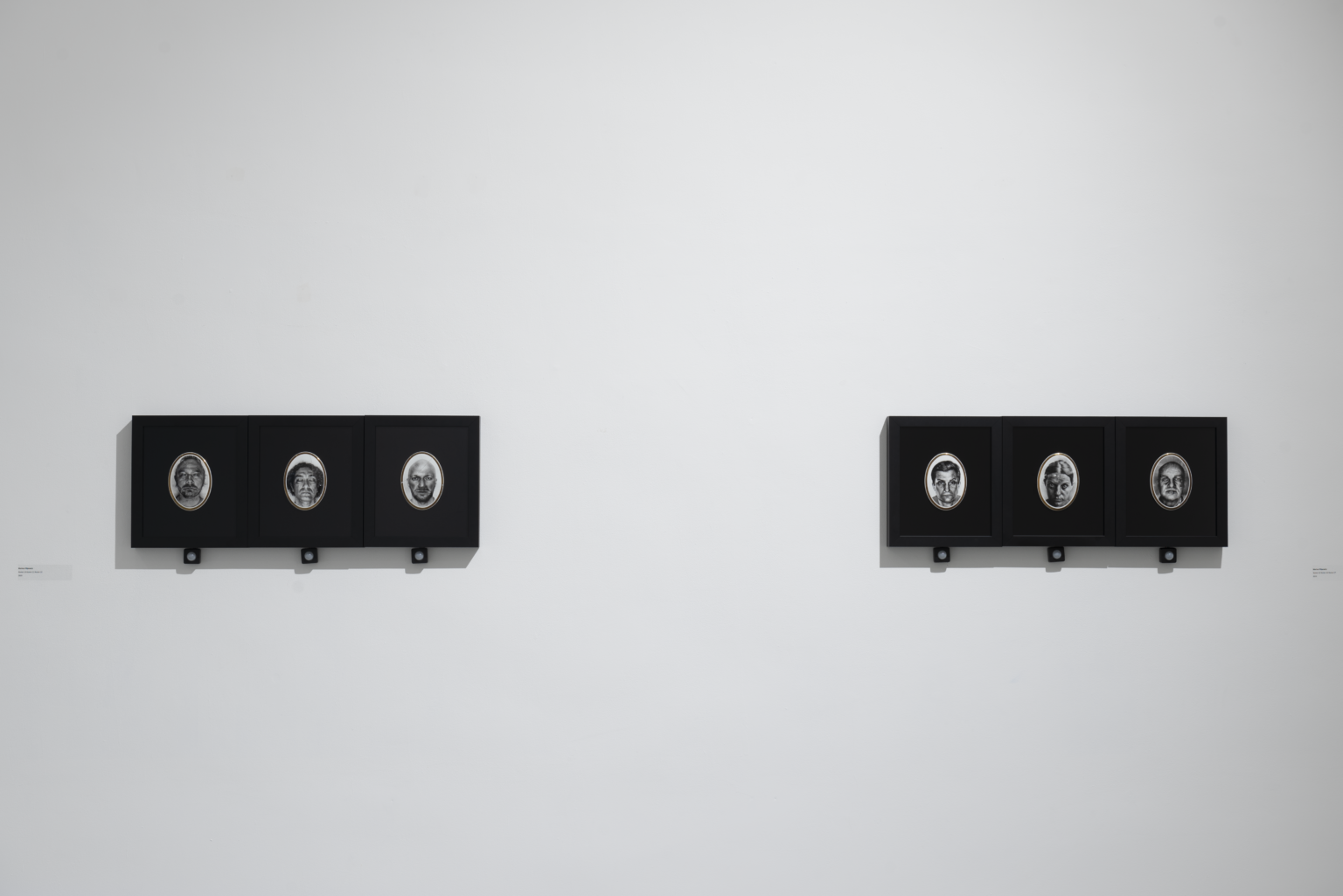 Sześć różnych twarzy w ciemnych ramkach na ekspozycji.