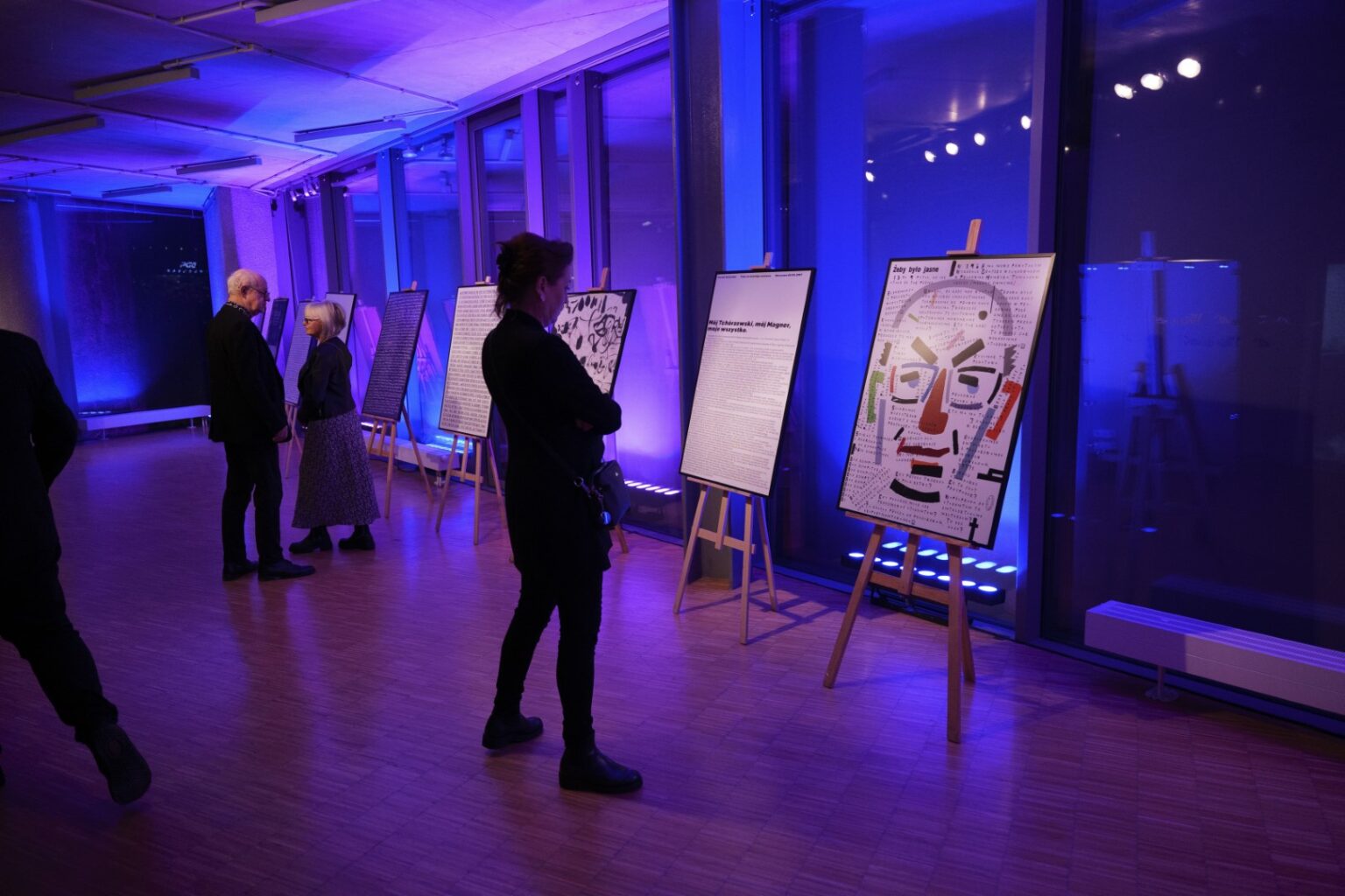 Kobieta przyglądająca się plakatom na sztalugach.