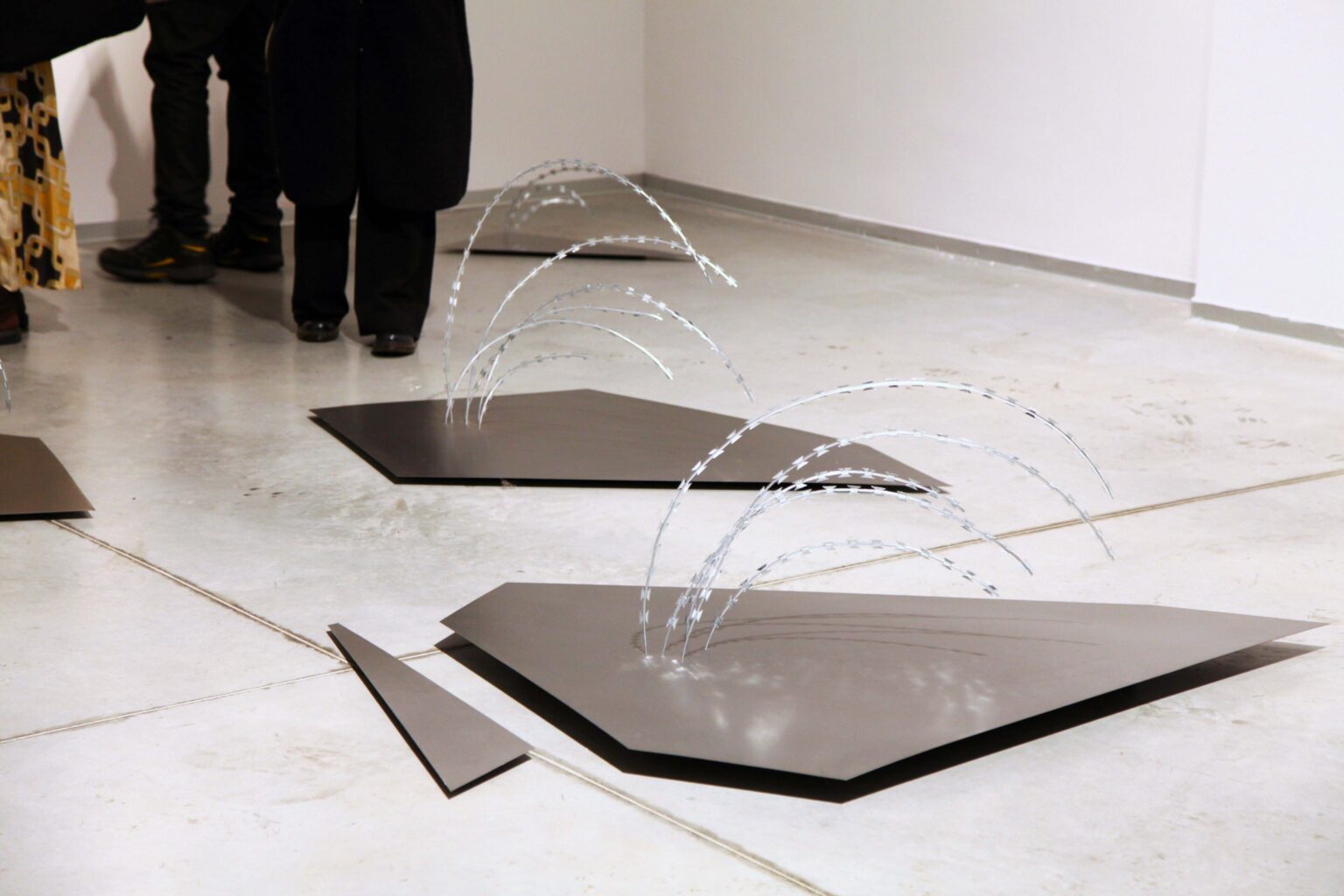 Dwa eksponaty z drutu ułożone na podłodze