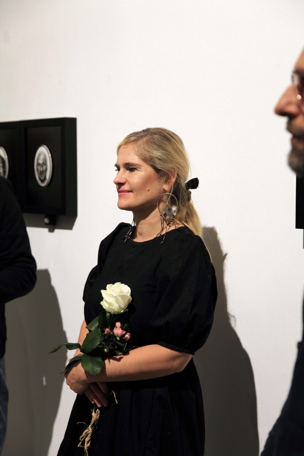 Kobieta z białą różą na tle wystawy