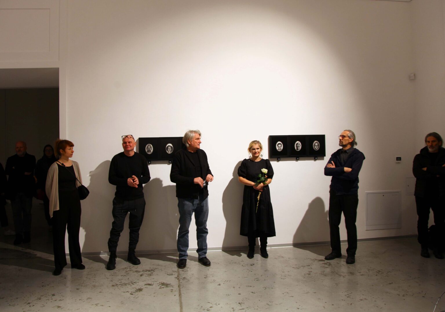 Piec osób stojących w rzędzie. Wystawa w tle.