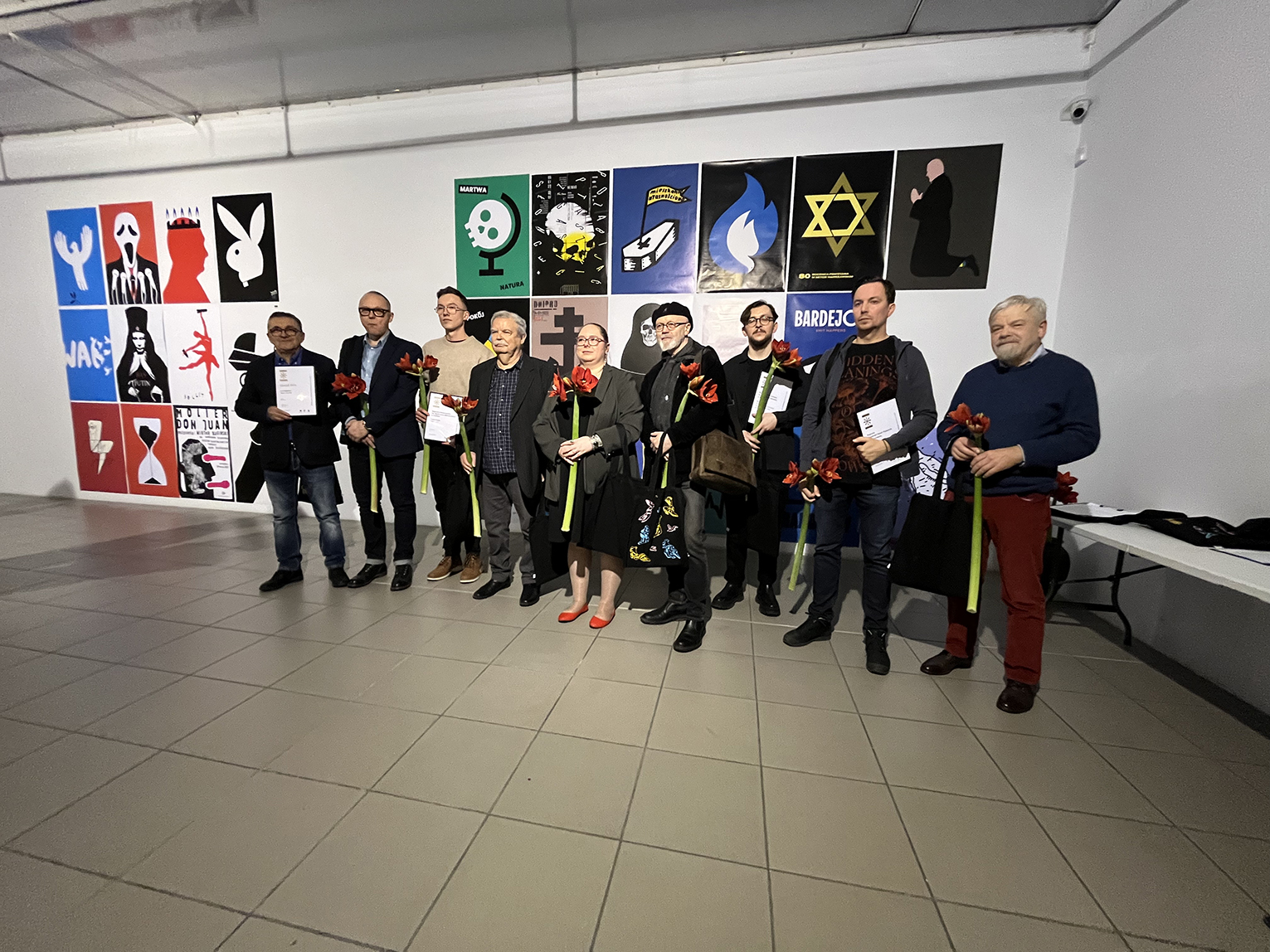 Grupa ludzi stojąca obok siebie na tle plakatów.