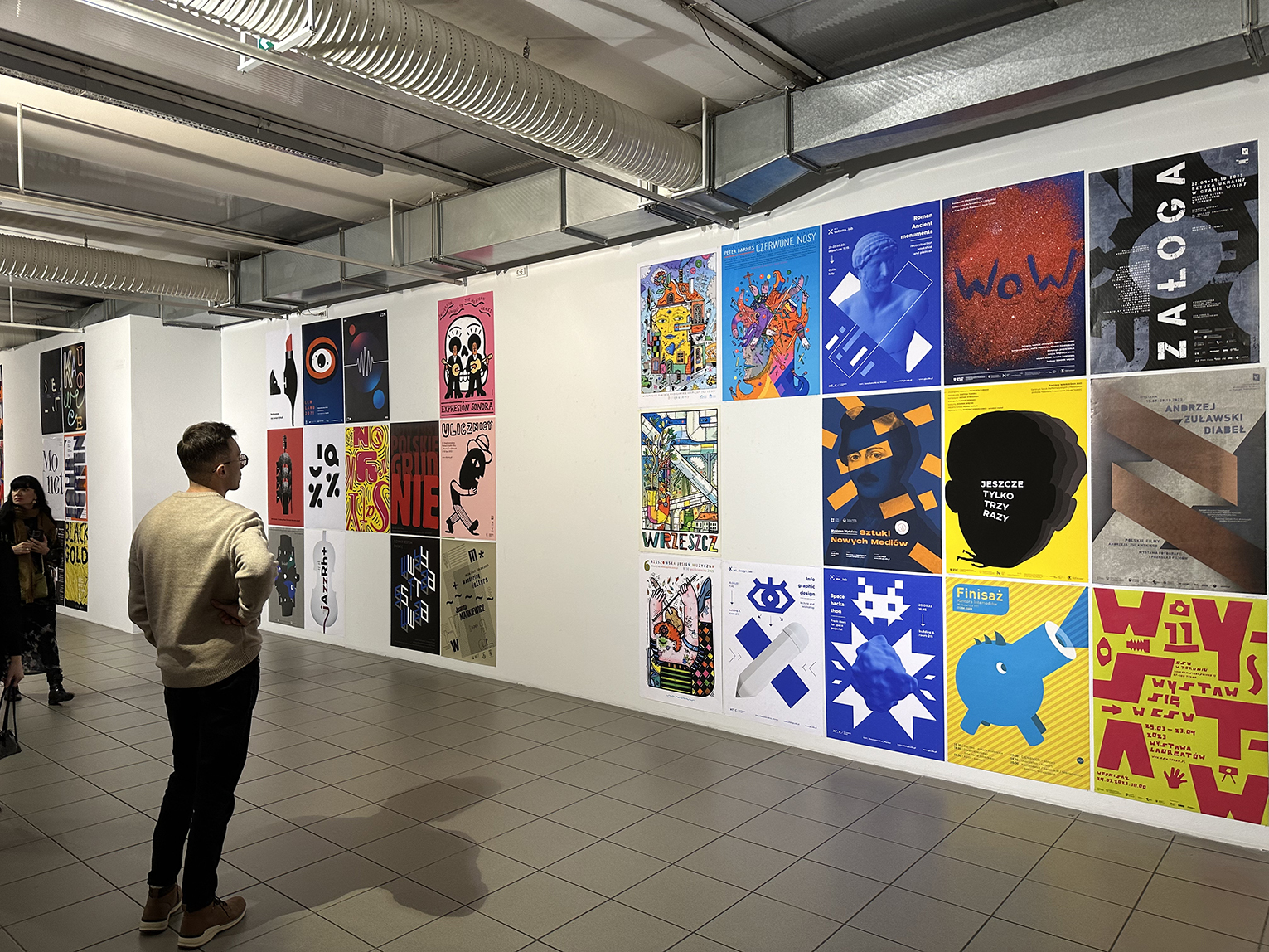 Mężczyzna stojący i podziwiający plakaty na wystawie.