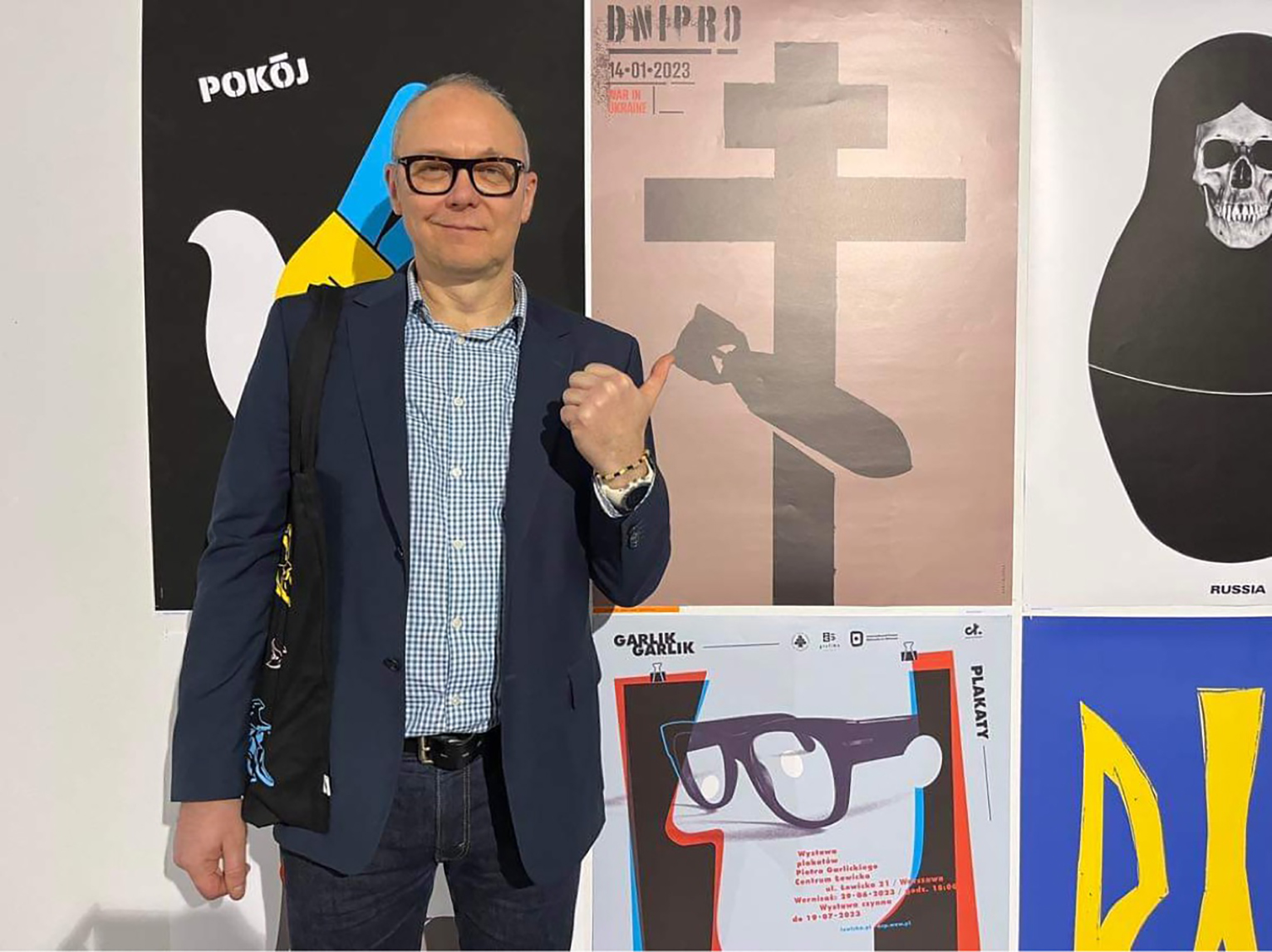 Mężczyzna stojący na tle plakatu swojego autorstwa.