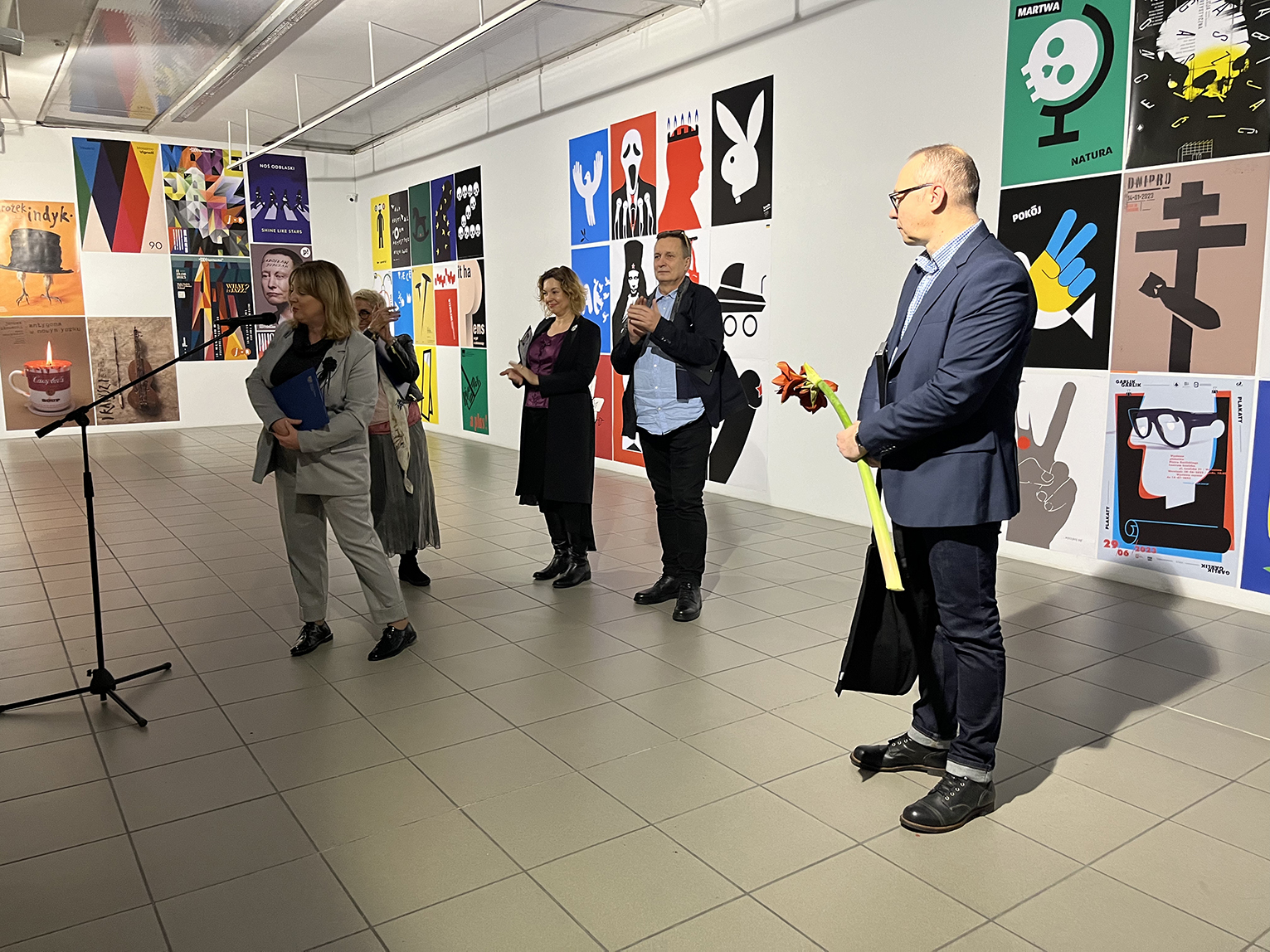 Grupa ludzi oglądająca plakaty na wystawie.