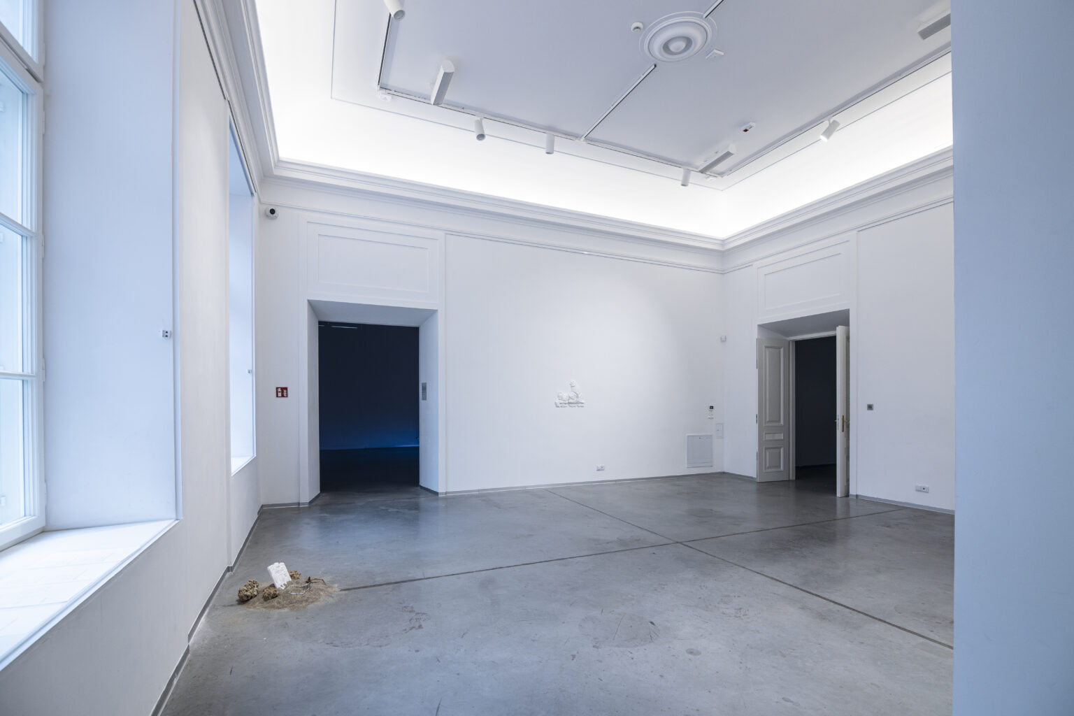 Widok sali galerii z zawieszonymi gipsowymi płaskorzeźbami wygenerowanymi przez sztuczną inteligencję.