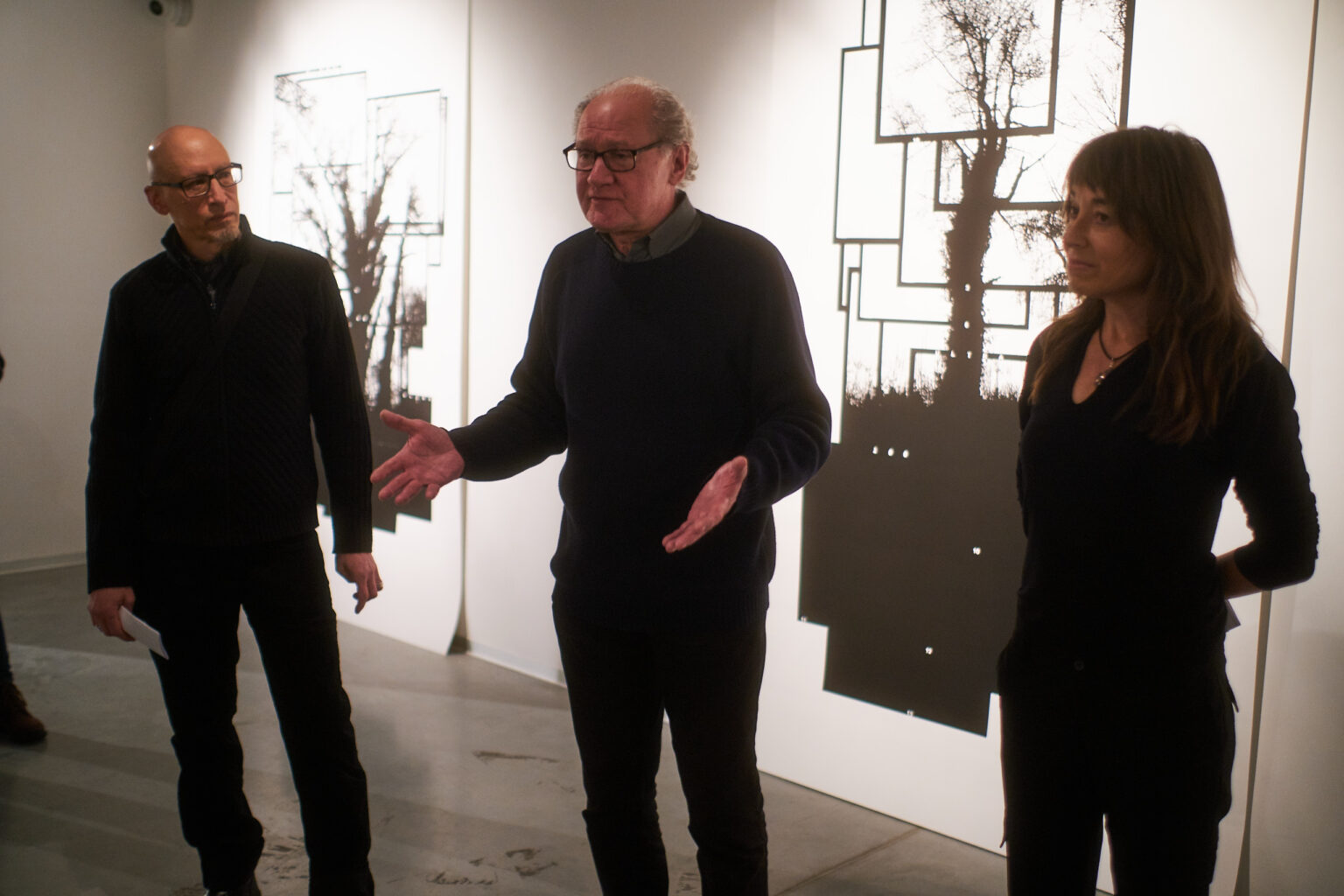 Otwarcie wystawy w galerii sztuki. Osoby słuchają wypowiedzi twórców wystawy