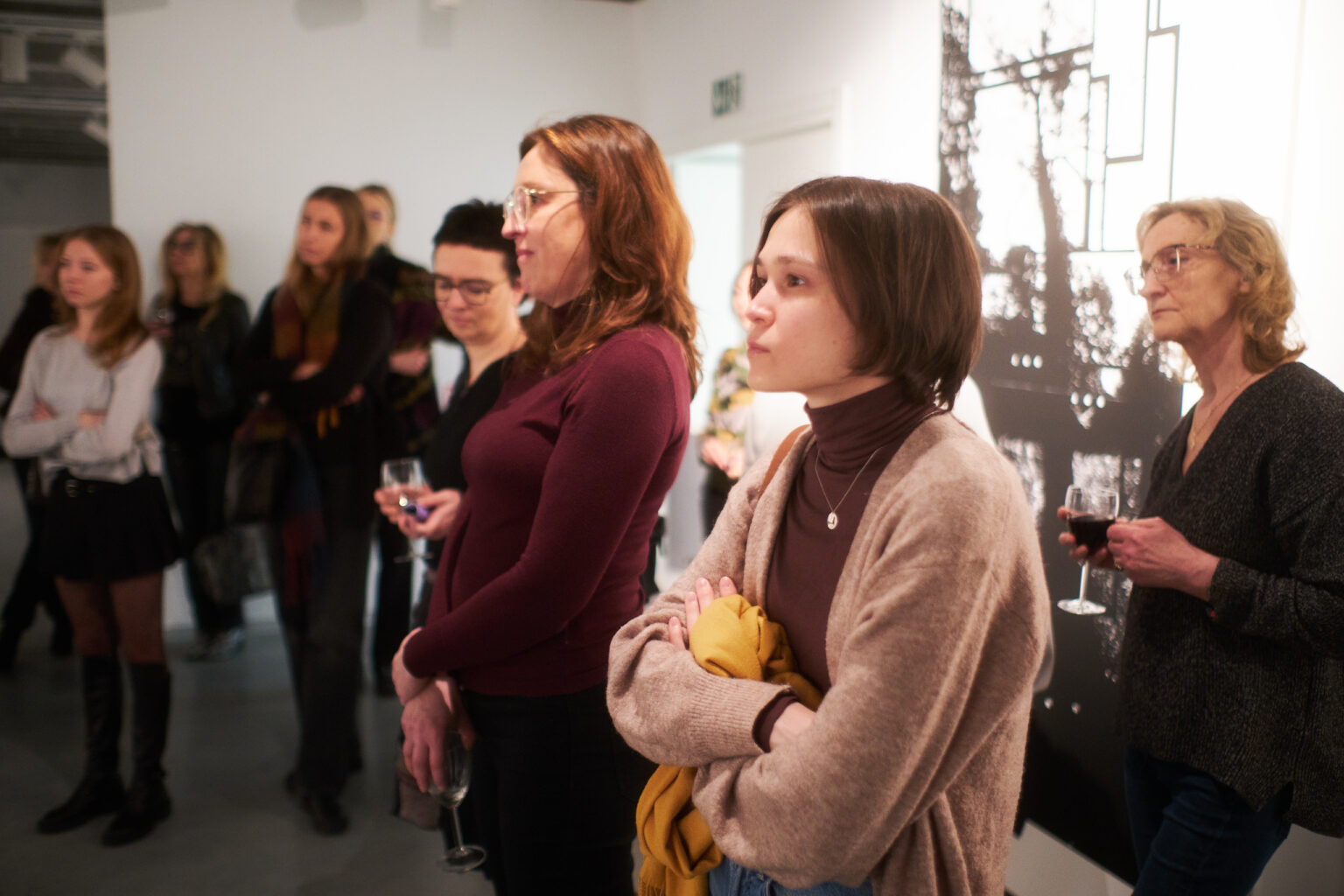 Otwarcie wystawy w galerii sztuki. Osoby słuchają wypowiedzi twórców wystawy