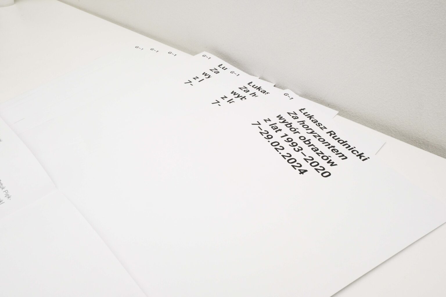 Foldery z tytułem wystawy na stole