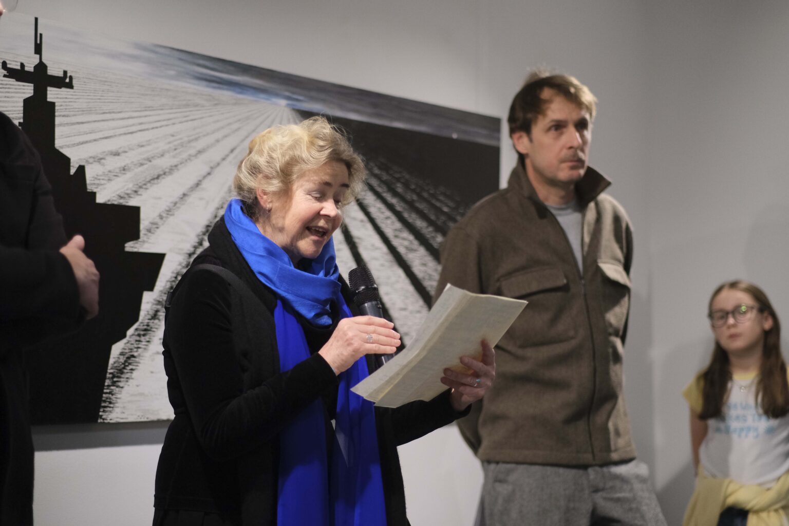 Kobieta i mężczyzna na tle obrazu. Kobieta mówi do mikrofonu