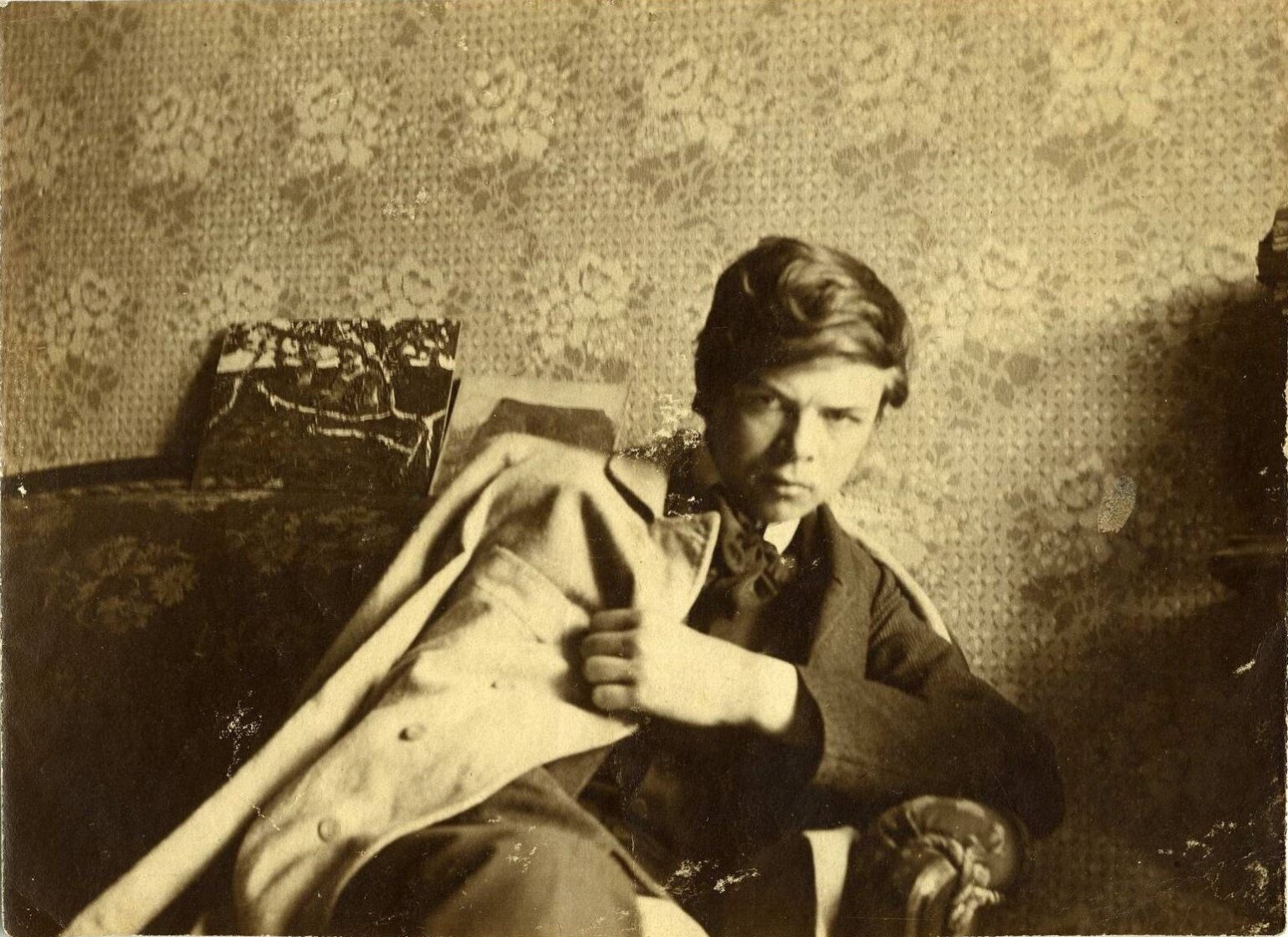 Portret (sepia) młodego, siedzącego mężczyzny z płaszczem zarzuconym na lewe ramię