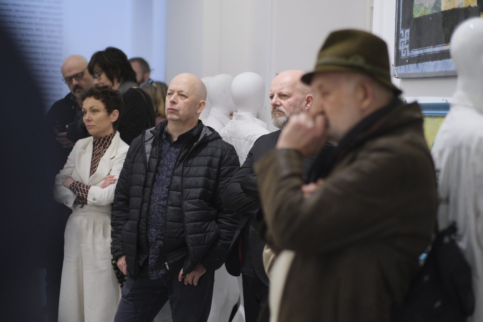 Kilka słuchających osób w przestrzeni wystawy