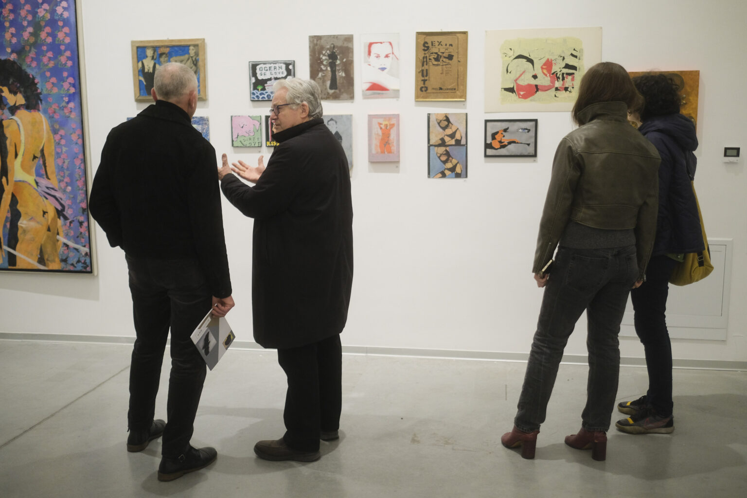 Trzy osoby odwrócone do nas tyłem oglądają ekspozycję