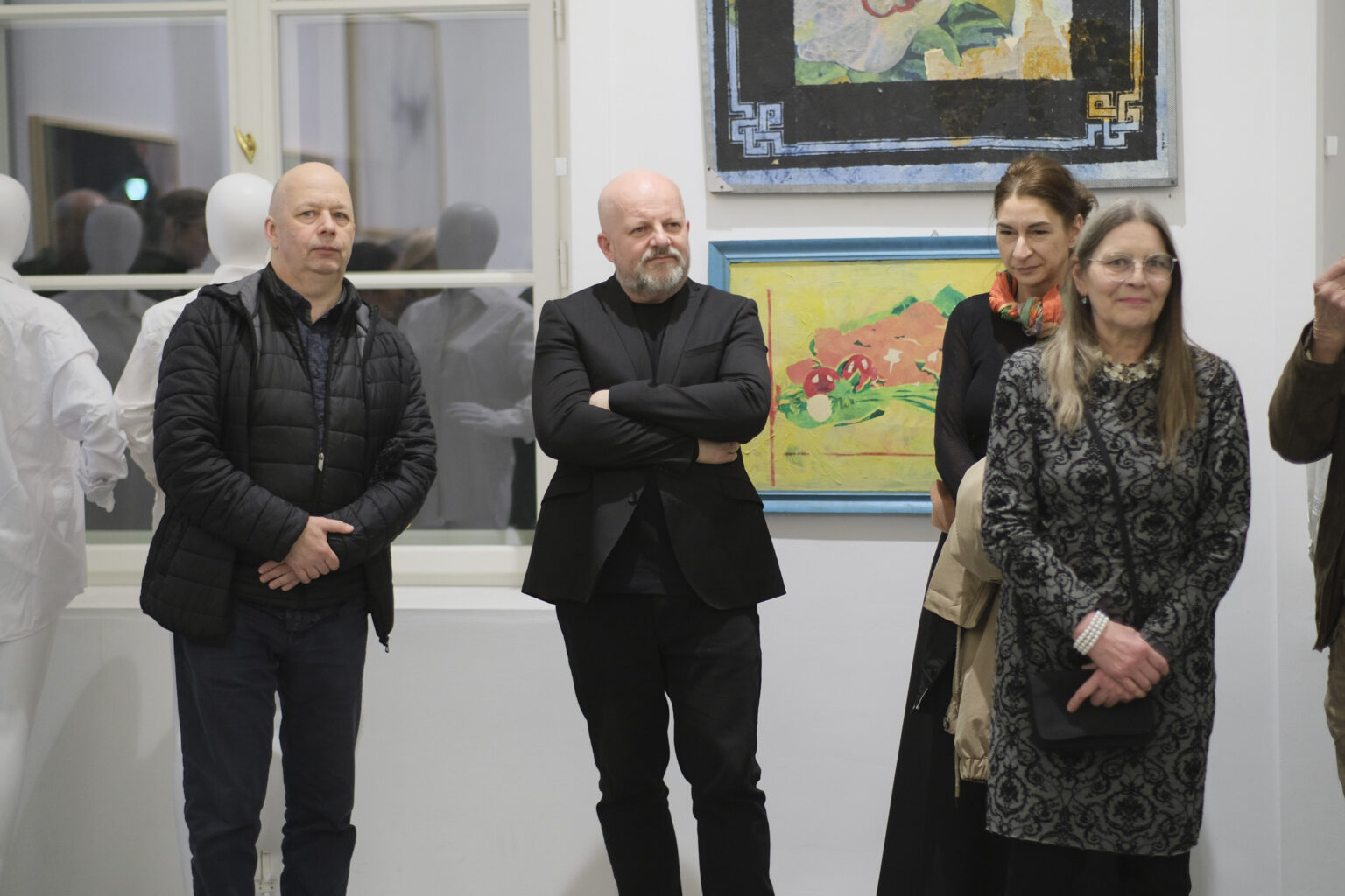 Kilka osób. W tle wystawa.