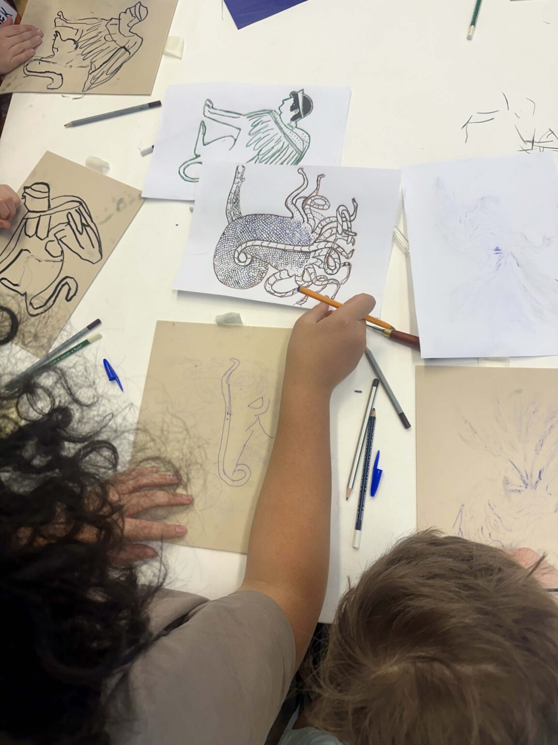 Dwoje dzieci rysuje przy stole. Przybory do rysowania