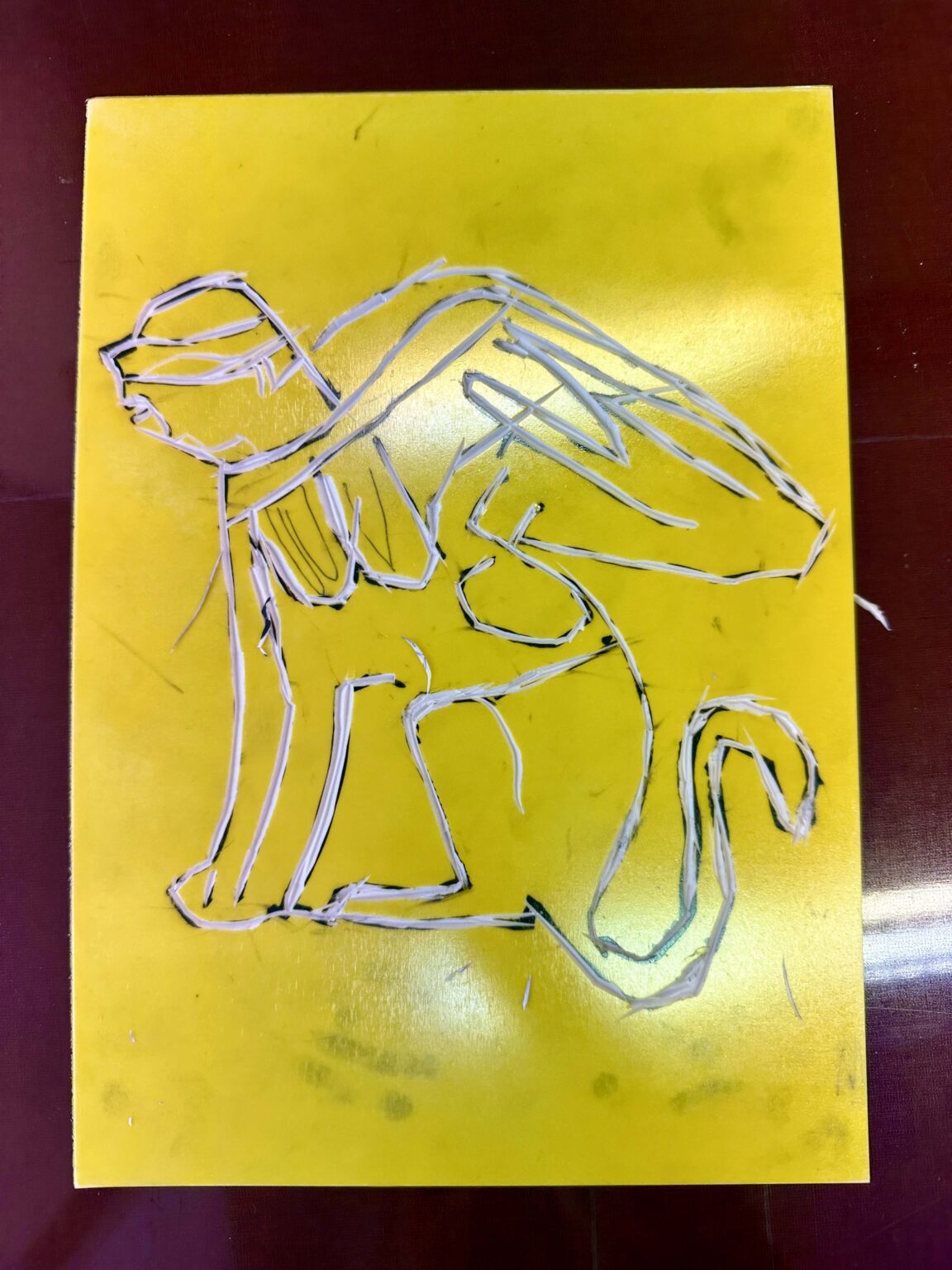 Grupa dzieci przy dużym stole podczas warsztatów. Na stole przybory do rysowania