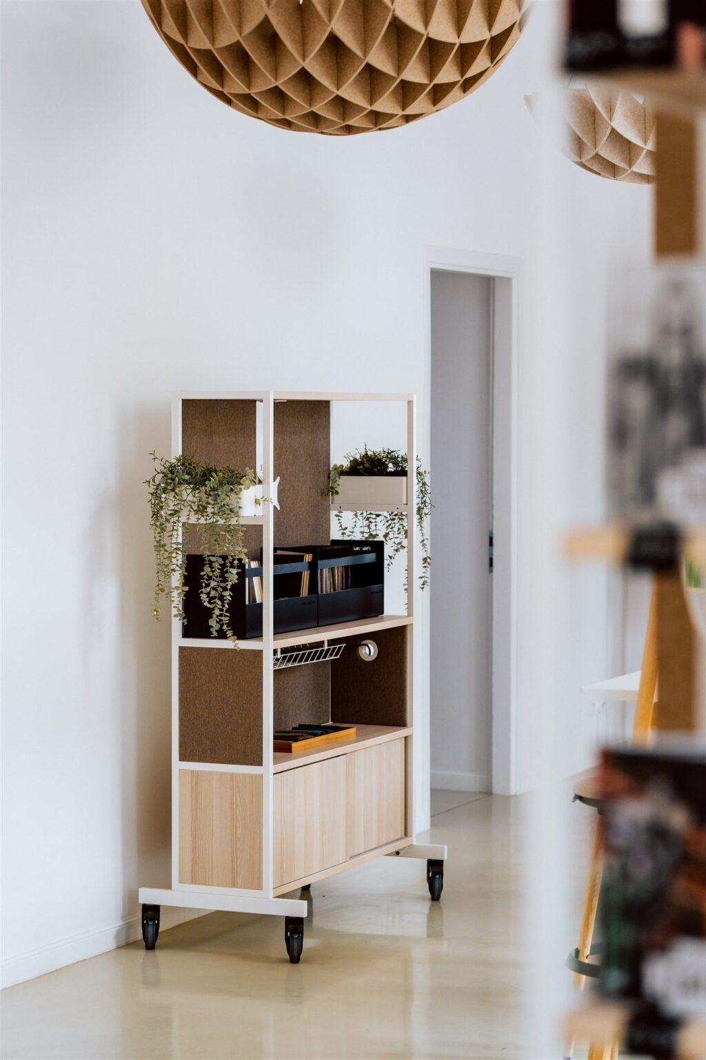 Nowoczesne, jasne wnętrze z niewielkim regałem i kulistą ozdobą