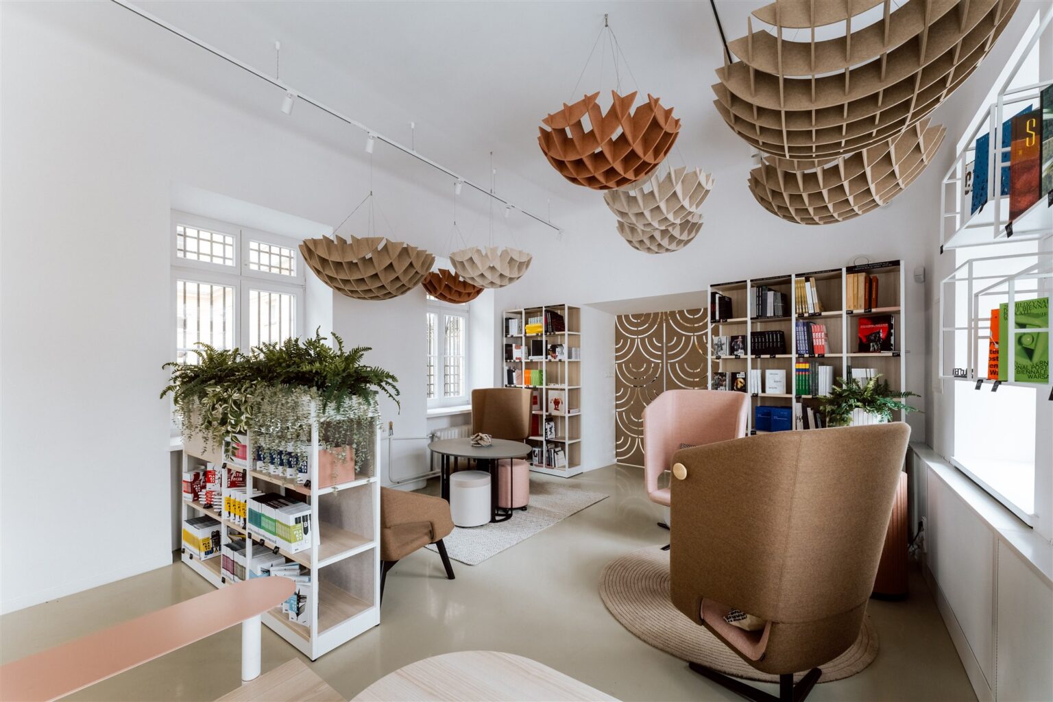 Nowocześnie umeblowane, jasne wnętrze z regałami pełnymi książek i kulistymi ozdobami podwieszonymi pod sufitem