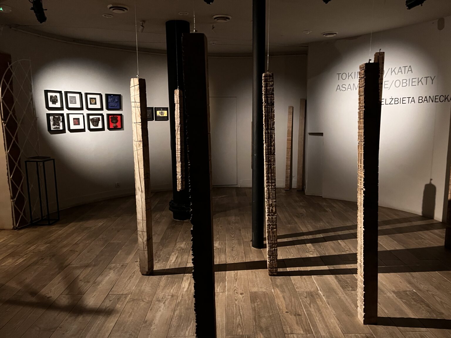 Widok galerii z pionowymi, drewnianymi elementami we wnętrzu