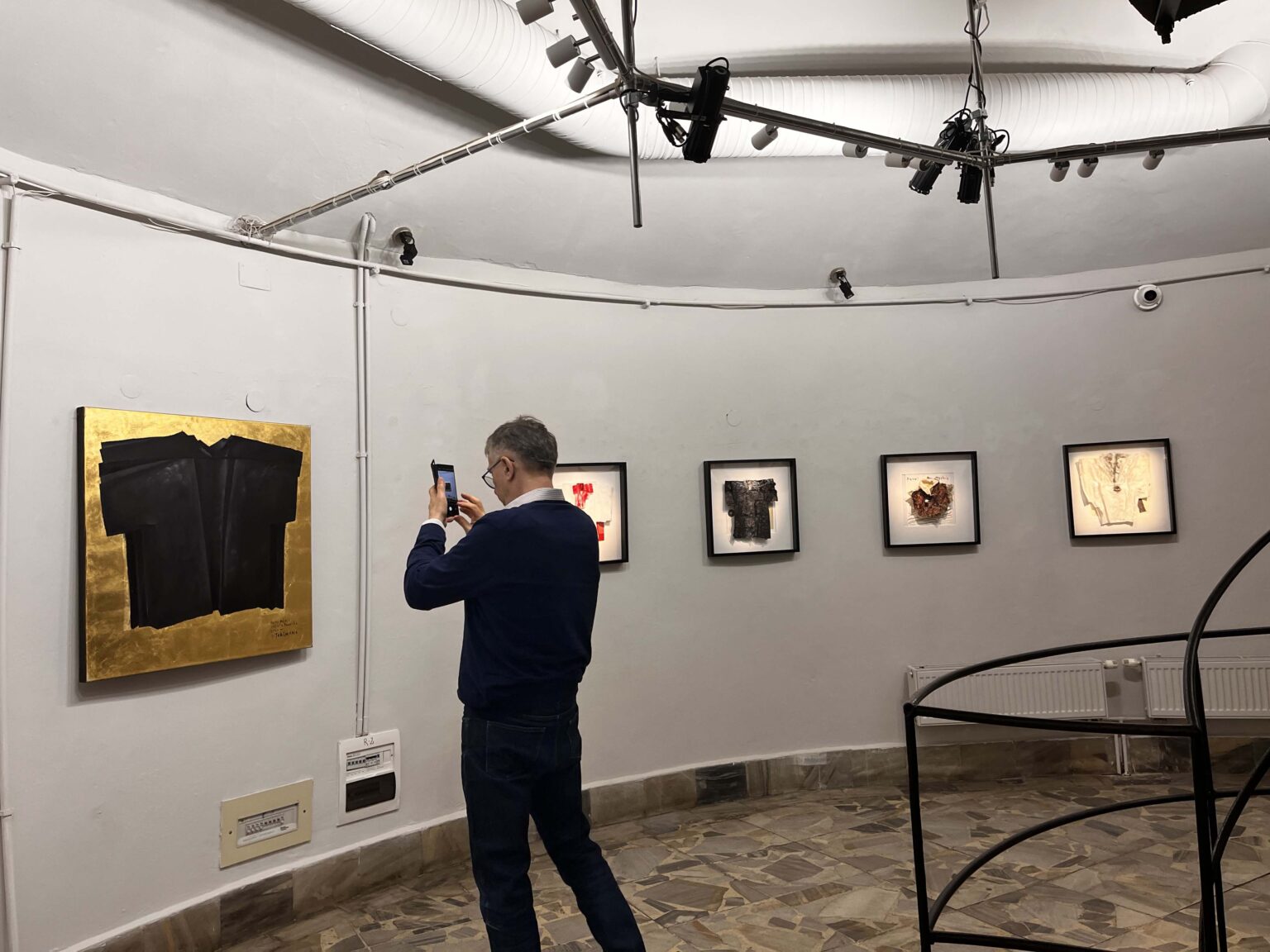 Widok galerii, po środku mężczyzna robiący zdjęcie telefonem