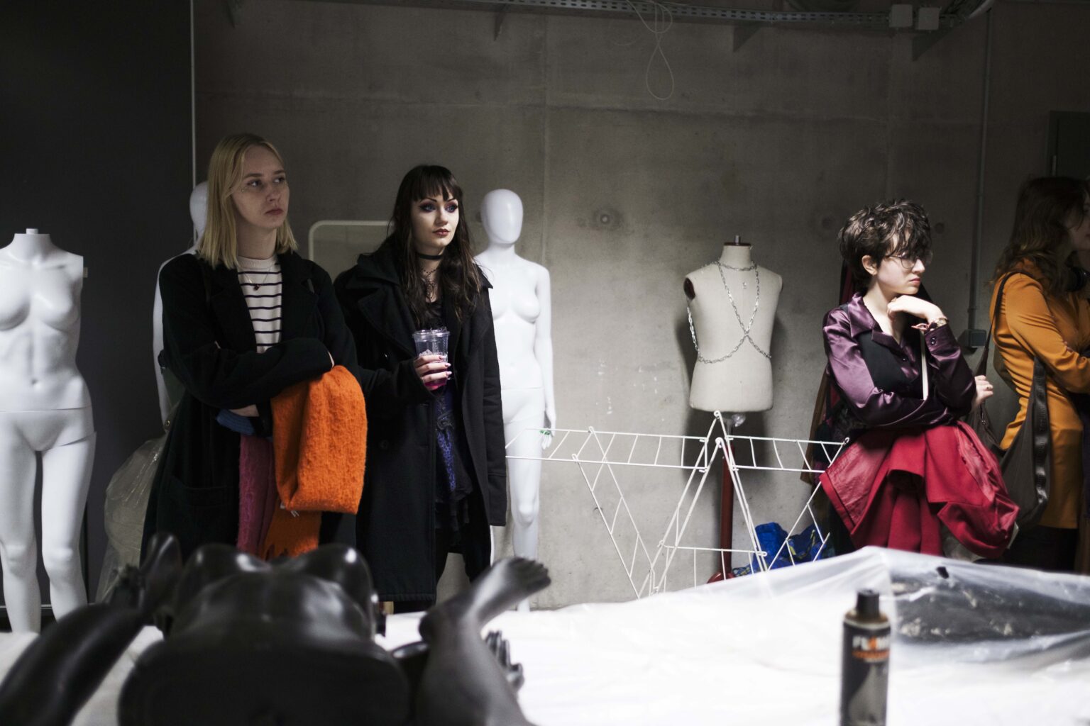 kilka osób w pracowni, manekiny w tle