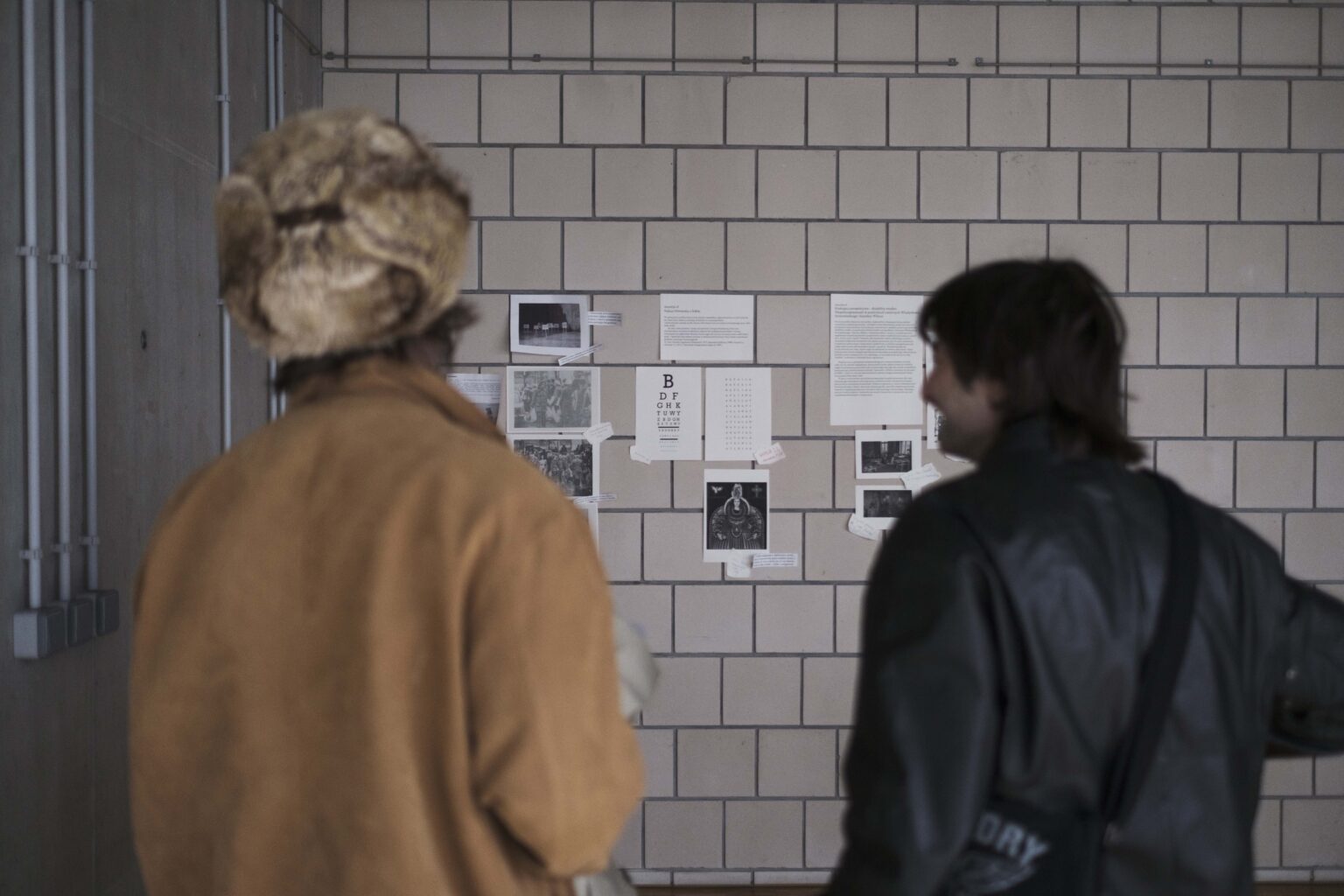 dwie osoby tyłem, oglądają zdjęcia na ścianie zdjęcia