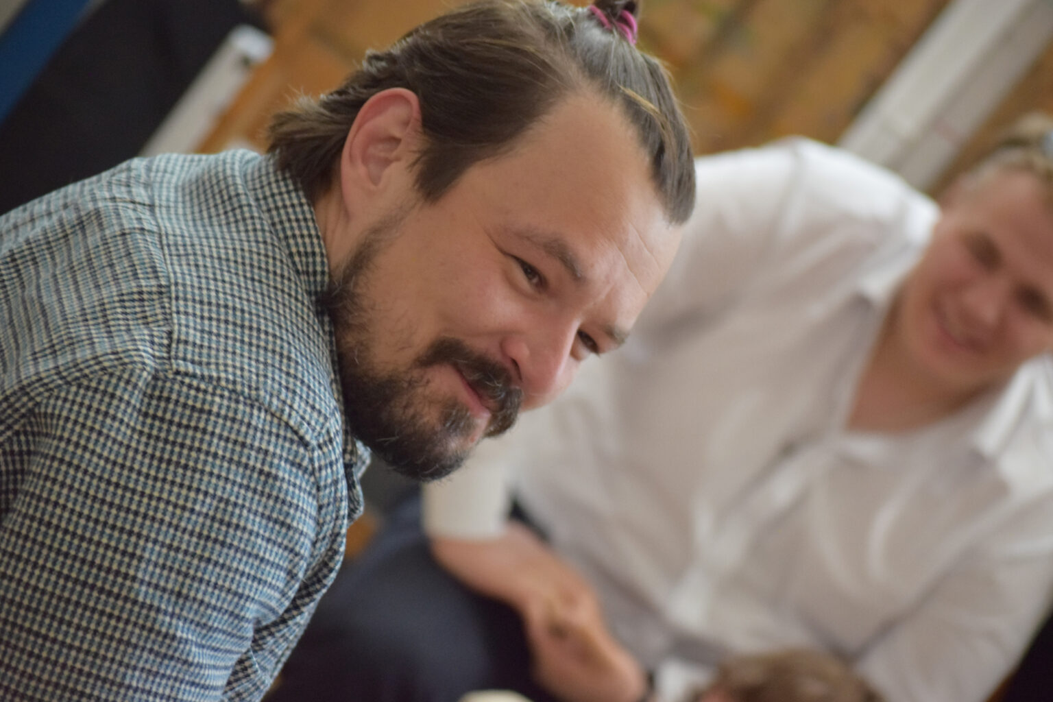 Zbliżenie uśmiechniętego mężczyzny z włosami związanymi w małą kitkę na czubku głowy