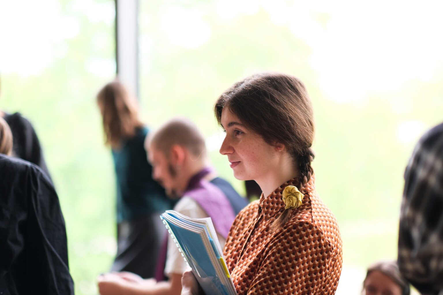 kobieta z warkoczami. W tle zwiedzający wystawę