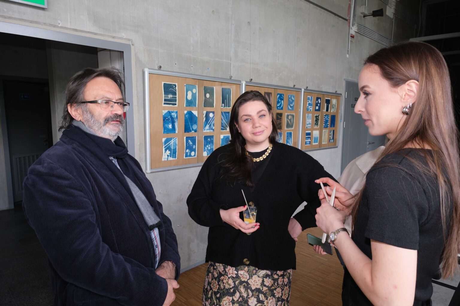 trzy osoby, wystawa w tle