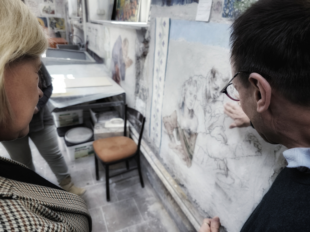 Osobyw pracowni. Mężczyzna (zdjęcie zza głowy) pokazuje coś po prawej stronie