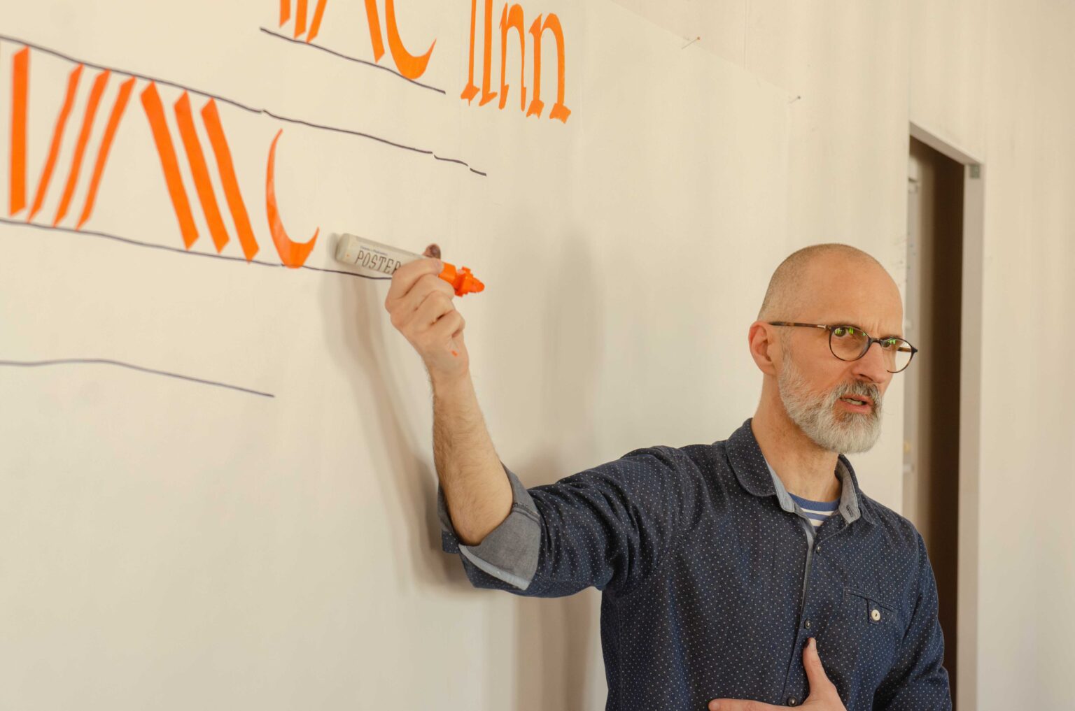 mężczyzna wskazujący pomarańczowe wykaligrafowane litery za swoimi placami