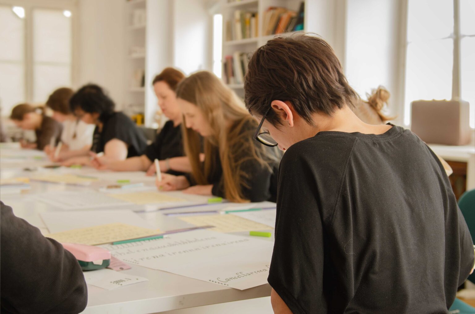 grupa osób przy stole kaligrafuje