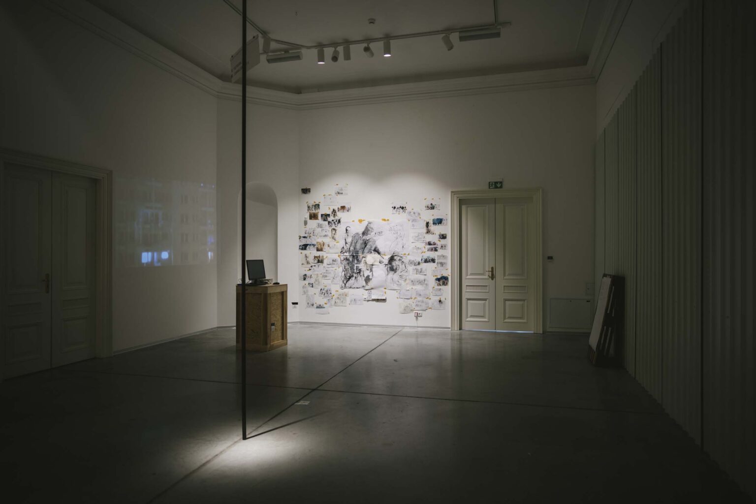 Pionowa instalacja złożona z krótkiej części rurki przytwierdzonej do podłogi; widok wystawy w tle