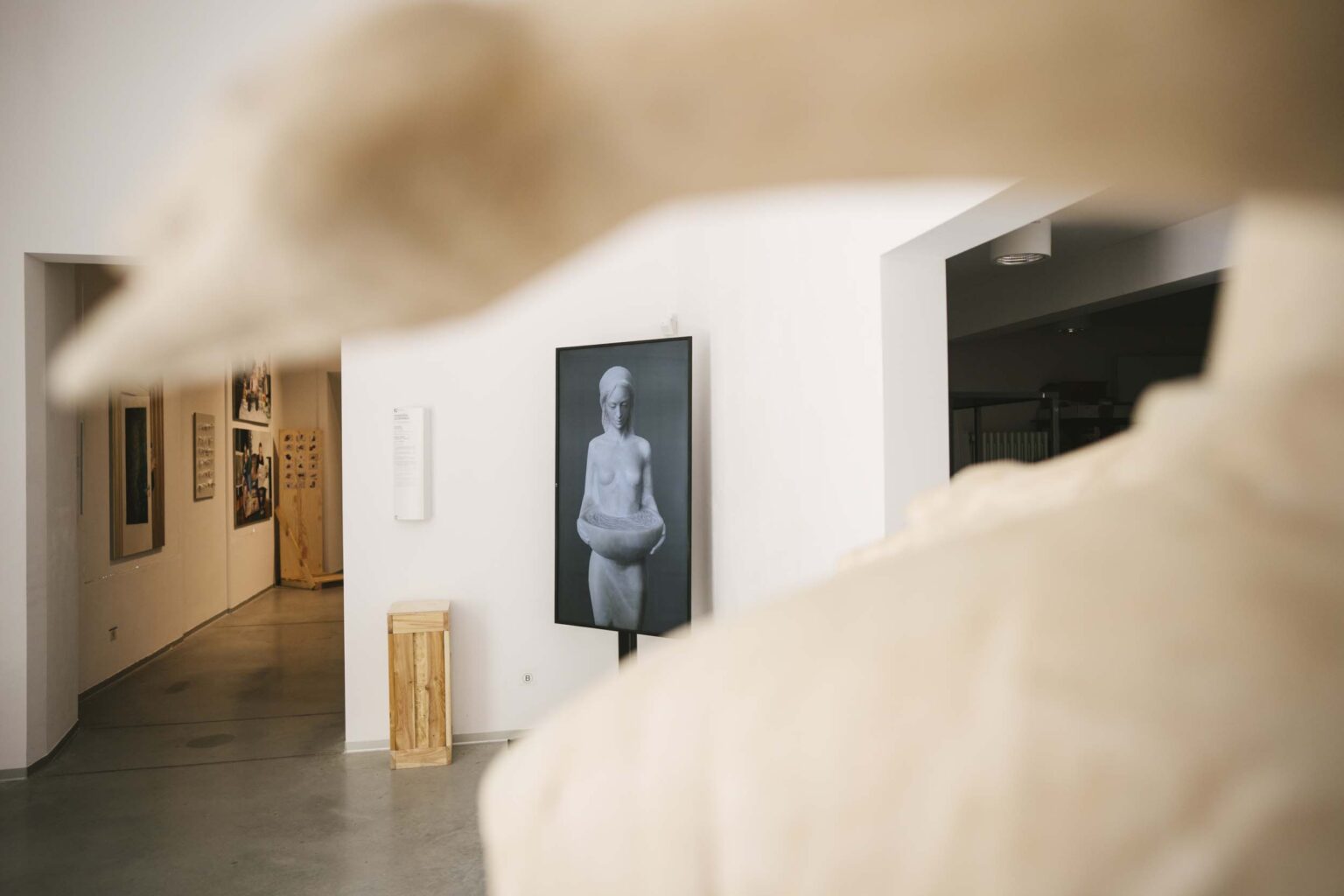 Fragment rzeźby, w tle: czarno-białe zdjęcie kobiety z misą