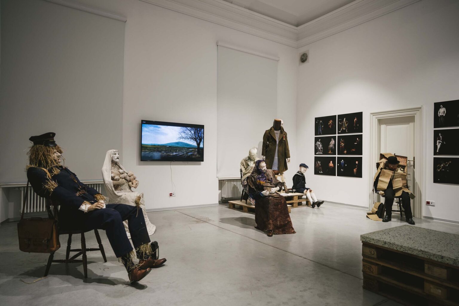 Sylwetki naturalnych rozmiarów siedzą w przestrzeni wystawy