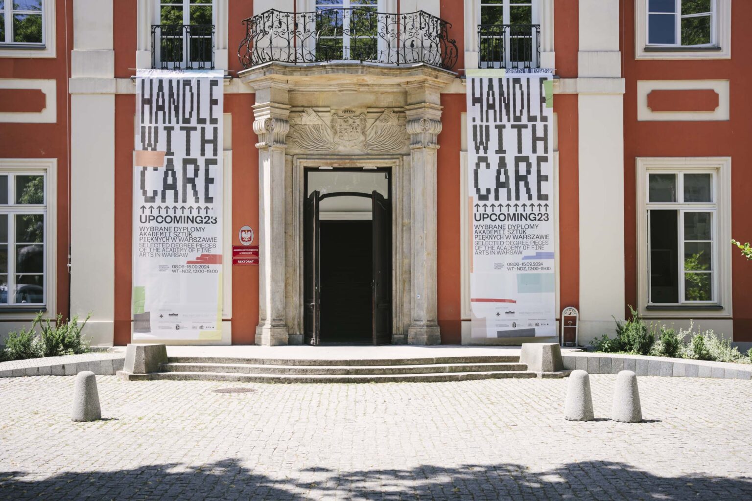 duże plakatu z nazwą wystawy po obu stronach wejścia do budynku