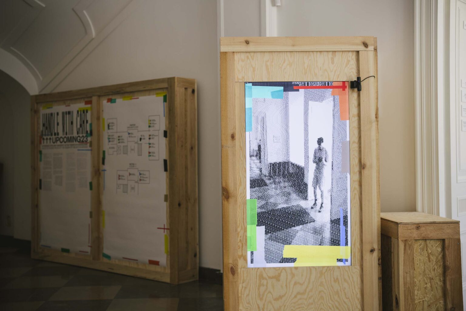 Drewniany kubik, z wmontowanym pionowym monitorem wyświetlający widok z kamery skierowanej przed kubik