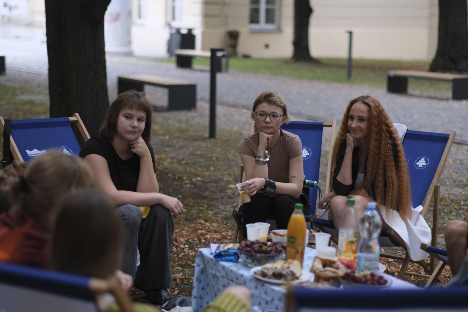 na zewnątrz: kilka osób na leżakach wokół stołu