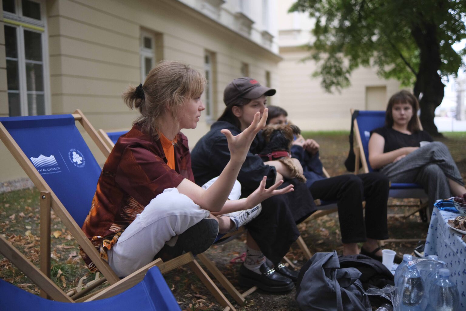 na zewnątrz: kilka osób na leżakach wokół stołu