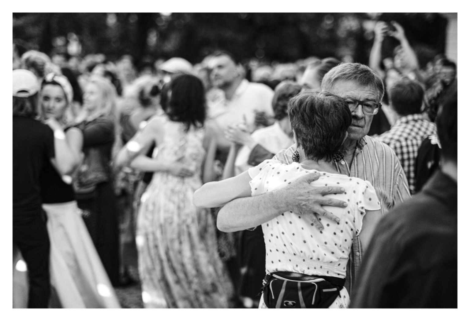 Starsza para tańcząca w tłumie.
