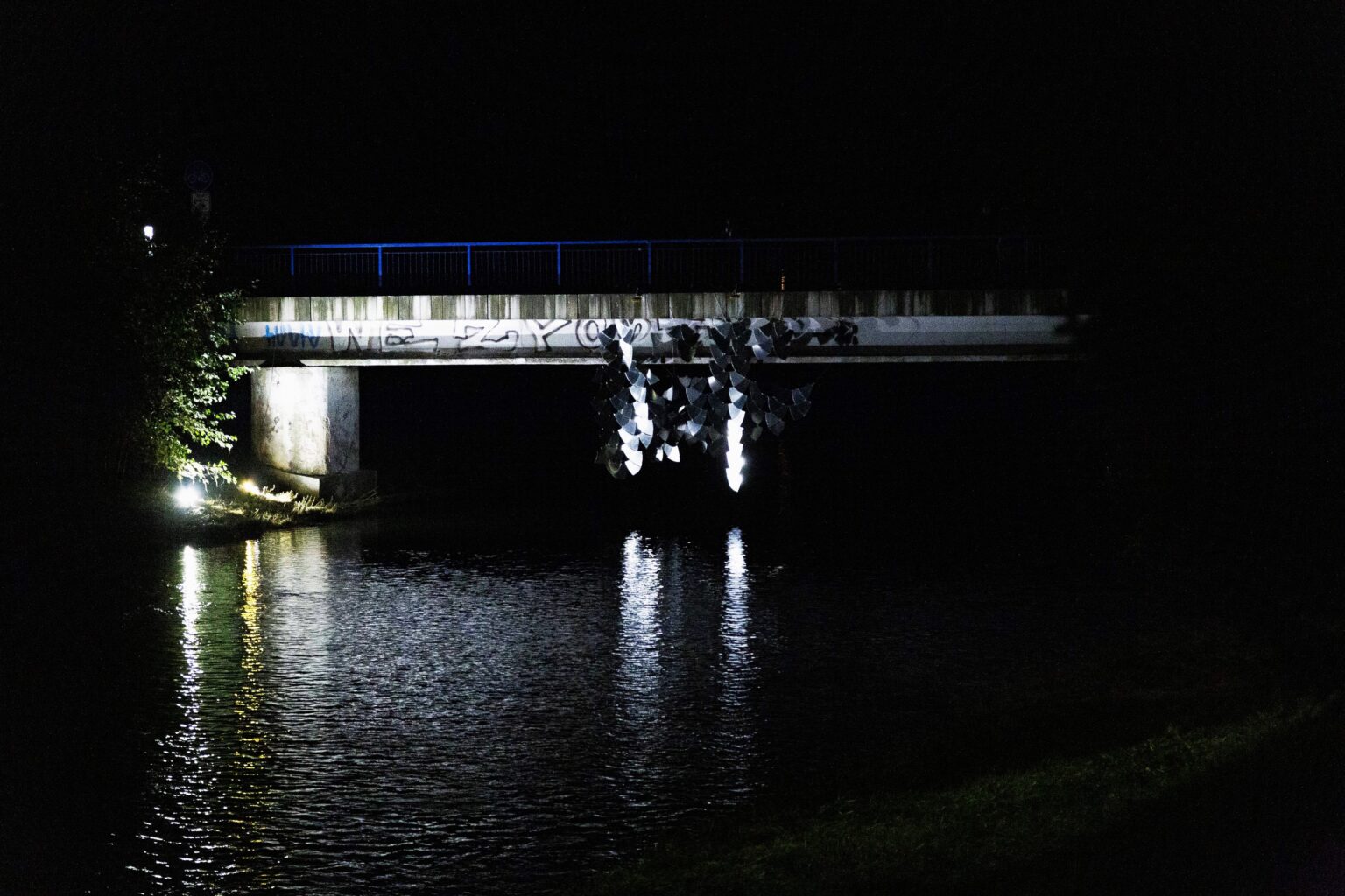 instalacja odbijająca światło powieszona na moście nocą