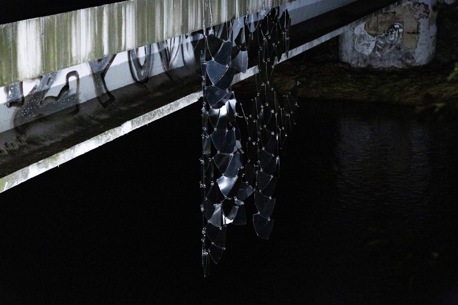 instalacja odbijająca światło powieszona na moście nocą