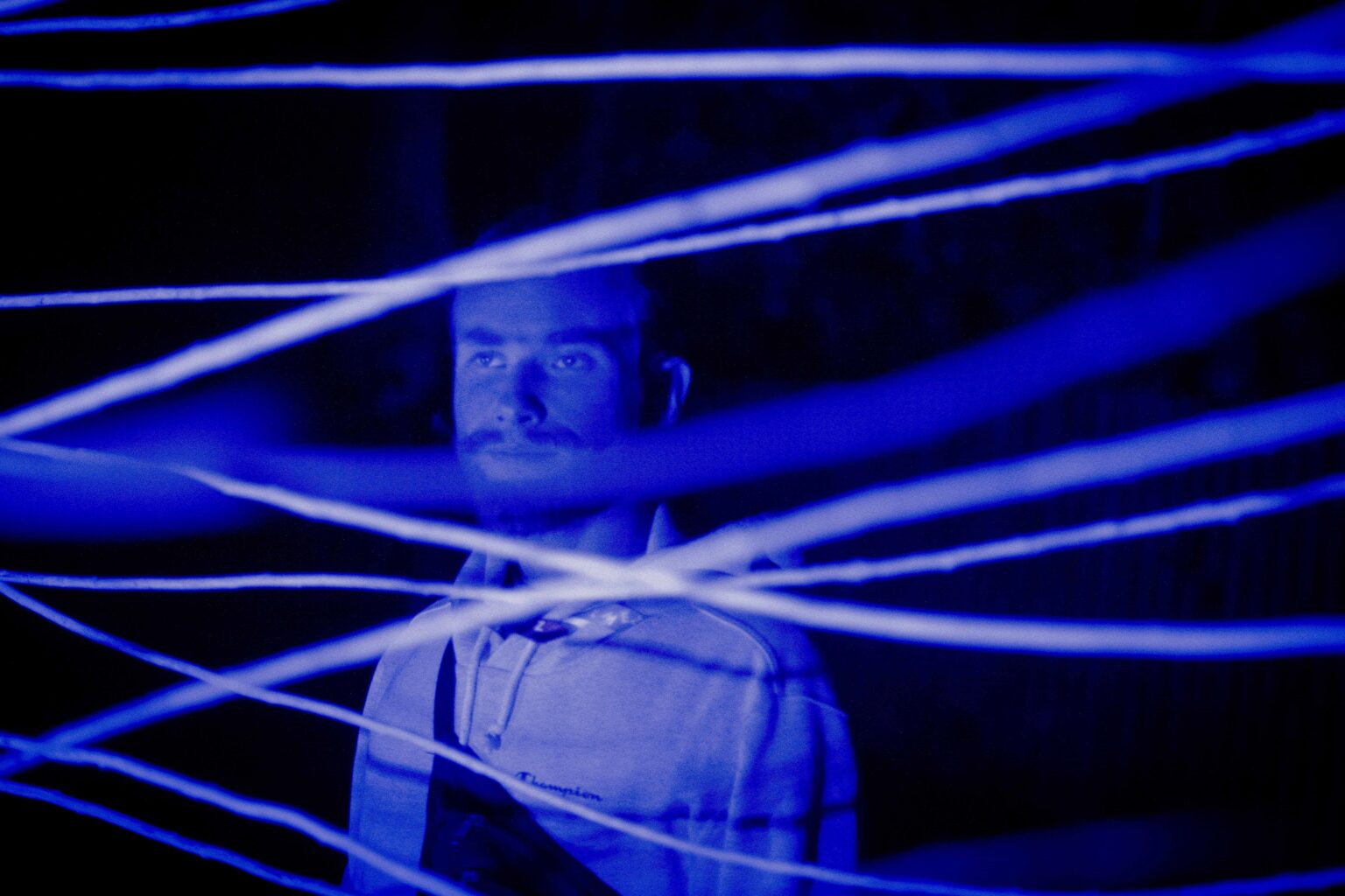 zbliżenie na twarz mężczyzny widzienej przez niebieską instalację świetlną