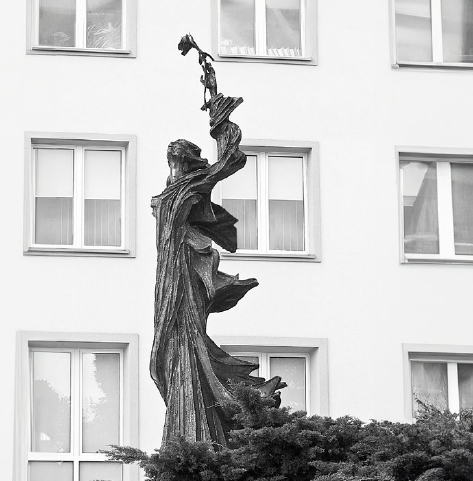 rzeźba kobiety na tle bloku mieszkalnego