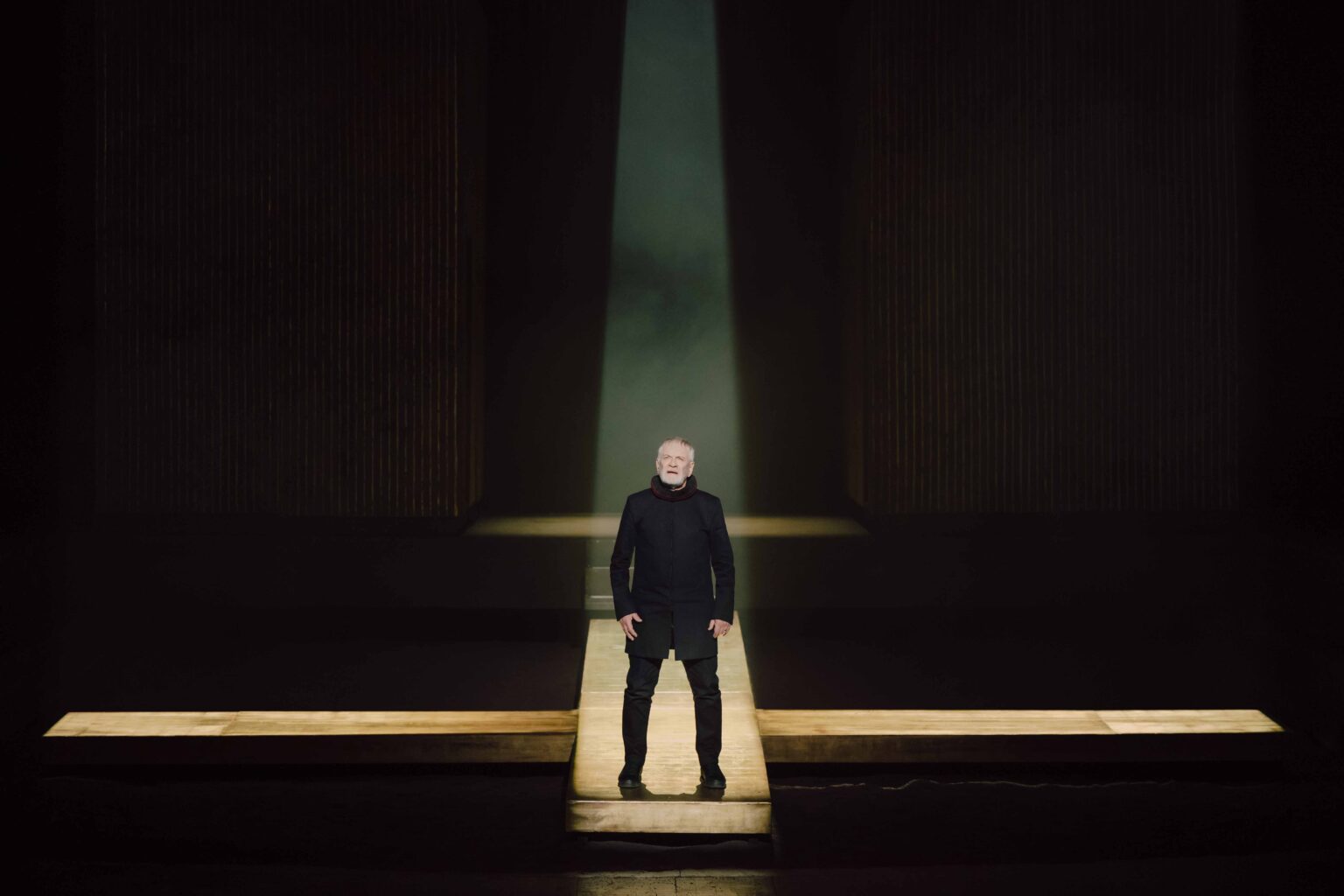 mężczyzna ubrany na czarno stoi w snopie światła