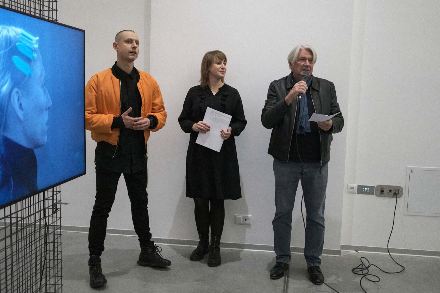 trzy osoby, jedna mówi do mikrofonu